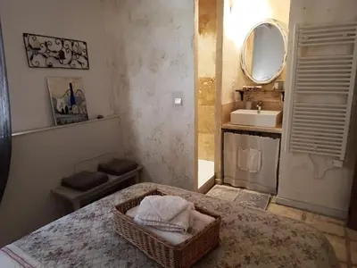 a bathroom with a bed with a mirror and a sink at Appartement en campagne au coeur du luberon in Roussillon