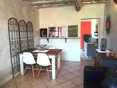 a kitchen and dining room with a table and white chairs at Appartement en campagne au coeur du luberon in Roussillon