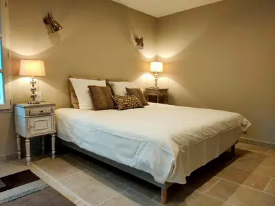a bedroom with a bed and a nightstand with two lamps at Le mas de Roussillon in Roussillon