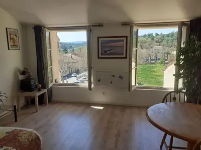 a living room with a table and two large windows at Maison restaurée à l'ancienne avec terrasse in Jouques