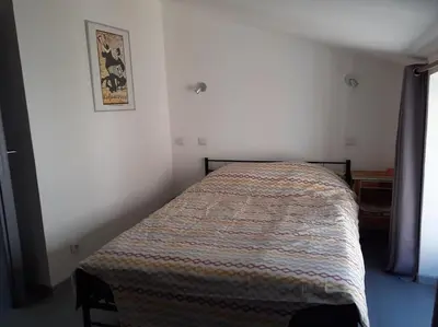a bedroom with a bed in a white room at Maison restaurée à l'ancienne avec terrasse in Jouques