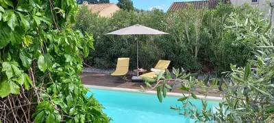 an umbrella and chairs next to a swimming pool at Les Myosotis Cavaillon/Petit Luberon in Cavaillon