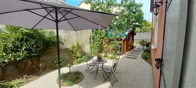 a patio with an umbrella and a table and chairs at Les Myosotis Cavaillon/Petit Luberon in Cavaillon