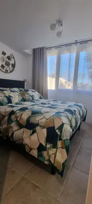a bedroom with a bed with a comforter and windows at LES BOIS DE ZOLA entre Provence et Luberon in Saint-Estève-Janson