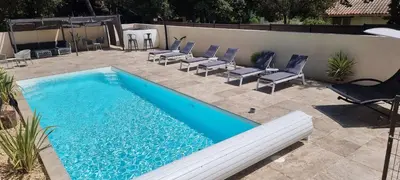 a swimming pool with lounge chairs next to a wall at LES BOIS DE ZOLA entre Provence et Luberon in Saint-Estève-Janson