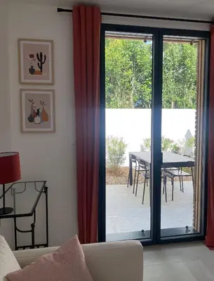 a living room with a sliding glass door with a table at Gîte cosy et tout équipé 