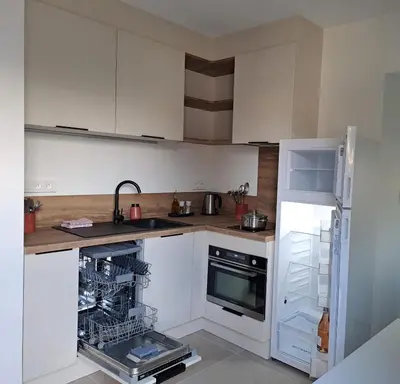 a kitchen with white cabinets and a dishwasher at Gîte cosy et tout équipé 