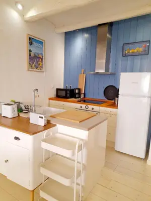 a kitchen with white cabinets and a white refrigerator at L'atelier au coeur du village in Roussillon
