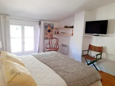 a bedroom with a bed and a flat screen tv at L'atelier au coeur du village in Roussillon