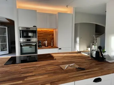 a kitchen with white cabinets and a wooden counter top at Maison d’Oléa in Bonnieux