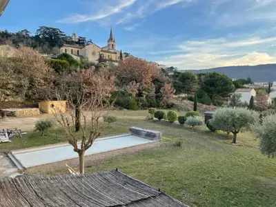 a view of a garden with a building on a hill at Maison d’Oléa in Bonnieux