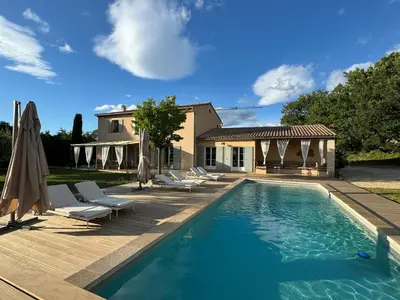 a swimming pool with chairs and a house at Maison d’Oléa in Bonnieux