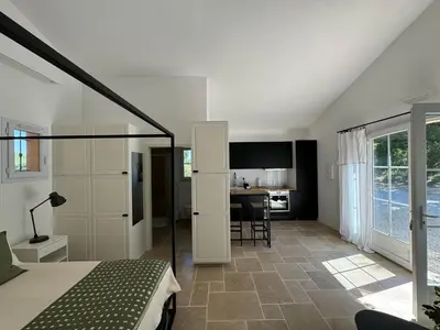 a bedroom with a bed and a kitchen with a table at Maison d’Oléa in Bonnieux