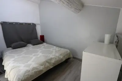 a small bedroom with a bed and a white wall at Le Gassendi Duplex in Aix-en-Provence