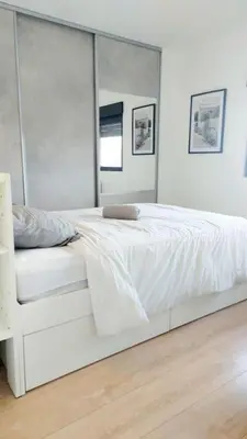 a white bed in a white bedroom with a mirror at 