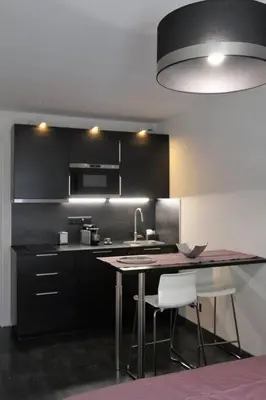 a kitchen with black cabinets and a table and chairs at STUDIO Mr&Mrs in Aix-en-Provence
