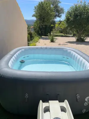 a jacuzzi tub with a bench in a yard at L Orchidée in Mormoiron