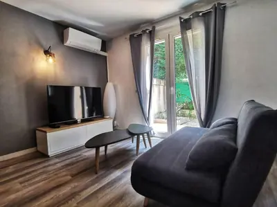 a living room with a couch and a flat screen tv at Les quatre loges - joli t2 jardinet et parking *3 in Aix-en-Provence