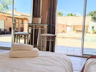 a bed with white sheets in a room with a large window at L'Escargolette - Incroyable maison de vacances 4 étoiles in Carpentras