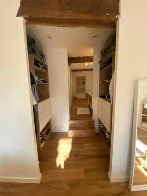 a walk in closet with white cabinets and wood floors at La Maison Jaune, une expérience inoubliable in Villes-sur-Auzon