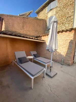 a patio with two beds and an umbrella at La Maison Jaune, une expérience inoubliable in Villes-sur-Auzon