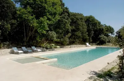 a swimming pool with two lounge chairs and trees at Appart Hôtel - Nature et Spa in Aurons