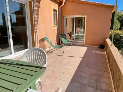 a patio with a green table and chairs on a house at La Villa Tanamera, très jolie maison piscine, à 2 pas du centre-ville in Bédoin