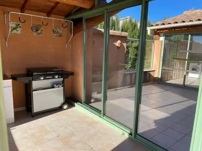 a screened in patio with a stove and some windows at La Villa Tanamera, très jolie maison piscine, à 2 pas du centre-ville in Bédoin