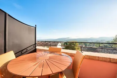 a wooden table and chairs on a balcony with an umbrella at Village Pont Royal en Provence - maeva Home - Appartement climatisé 2 pièces 4 personnes - Sélection MAE-2601 in Mallemort