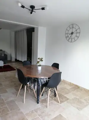 a dining room table with chairs and a clock on the wall at Joli studio calme et moderne in Pertuis
