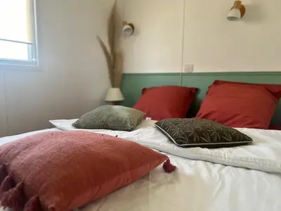 a bed with red and green pillows on it at Cabane la Clef des Champs au Mas des Entrages in Salon-de-Provence
