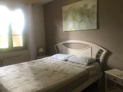 a bedroom with a bed with a white headboard and a window at VILLA AVEC PISCINE in Roussillon