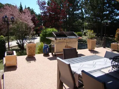 a patio with a grill and a table and chairs at VILLA AVEC PISCINE in Roussillon