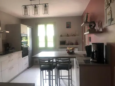 a kitchen with a counter and two bar stools at VILLA AVEC PISCINE in Roussillon