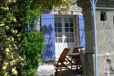 a table and chairs in front of a blue building at Bastide le Seigneur in Sault-de-Vaucluse