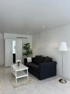 a living room with a black couch and a table at T3 avec jardin et piscine privée in Velaux