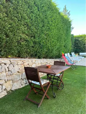a wooden table and chairs sitting next to a stone wall at T3 avec jardin et piscine privée in Velaux