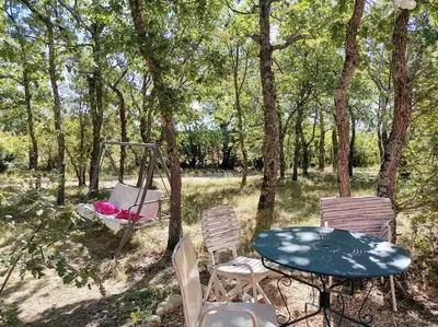 a patio with a table and chairs in the woods at Luberon : maison près de Joucas et Gordes in Joucas
