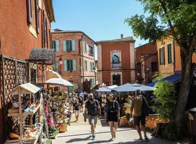 a group of people walking down a street at Appartement centre village in Roussillon