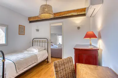 a bedroom with a bed and a table with a lamp at Hôtel Restaurant Les Remparts in Venasque