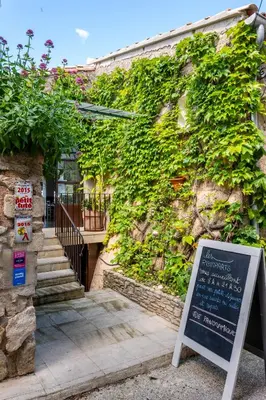 a building with a green wall with a sign next to it at Hôtel Restaurant Les Remparts in Venasque