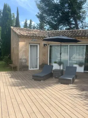 a deck with two chairs and an umbrella at Le p’tit bonheur-Piscine chauffée-clim-Park in Carpentras