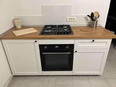a kitchen with white cabinets and a black stove at Soleil d’ocre - Bastide à Roussillon in Roussillon
