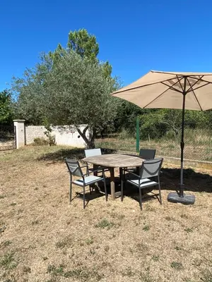 a wooden table with chairs and an umbrella at Soleil d’ocre - Bastide à Roussillon in Roussillon