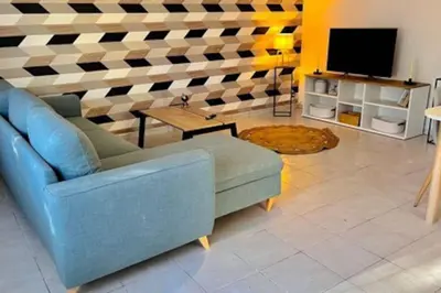 a living room with a blue couch and a tv at Soleil d’ocre - Bastide à Roussillon in Roussillon