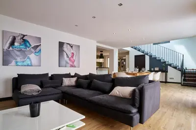 a living room with a black couch and a staircase at Maison de ville moderne climatisée avec piscine in Morières-lès-Avignon