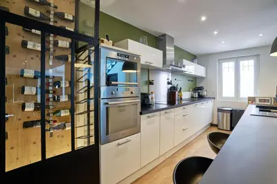 a kitchen with white cabinets and a counter with chairs at Maison de ville moderne climatisée avec piscine in Morières-lès-Avignon