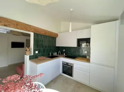 a kitchen with white cabinets and a green wall at Magnifique appartement + terrasse au cœur d’Aix in Aix-en-Provence