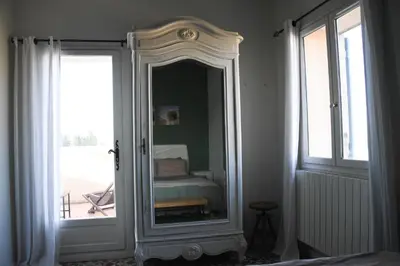 a mirror in a room with a bed and a window at Mas Gardane in Pernes-les-Fontaines