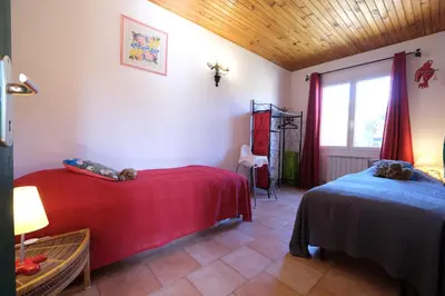a bedroom with two beds with red sheets and a window at pretty detached villa with private swimming pool, in Aureille, in the alpilles - 8 people in Aureille